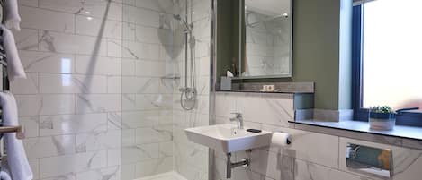 Une salle de bain moderne avec une douche à parois de verre, un lavabo avec un miroir au-dessus et des toilettes.