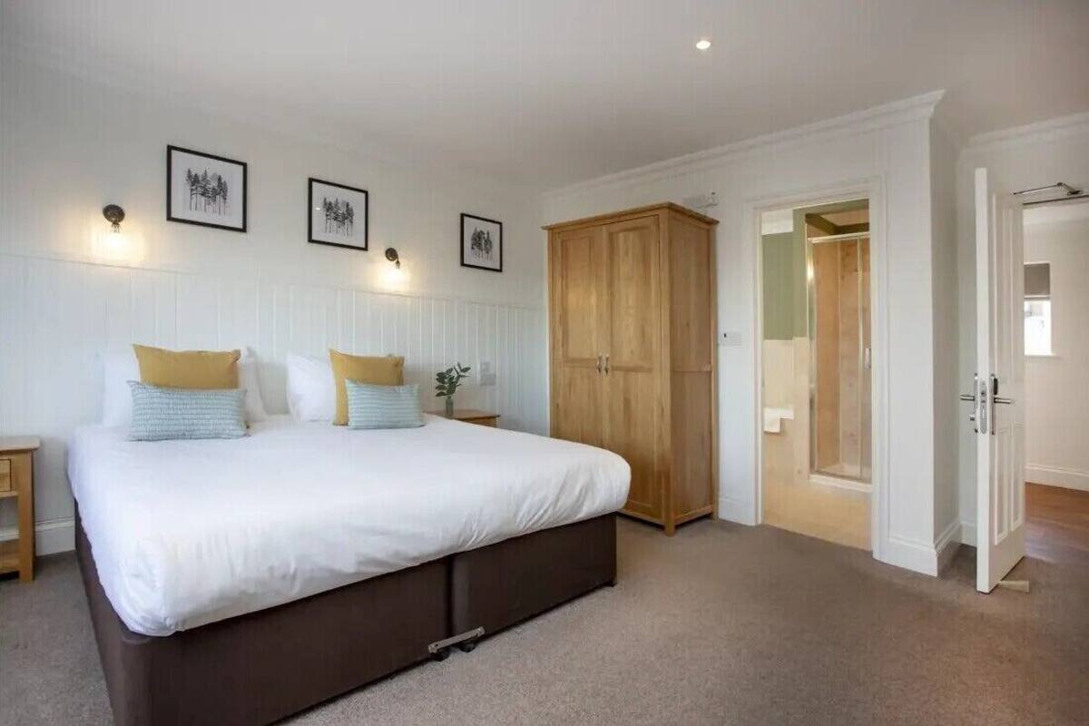 A bedroom with a large bed, a wardrobe, and a door leading to another room.