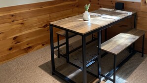 A corner room with a wooden bench, a table with a vase, and a sign reading "Cabin Life". - Lake & Mount Sunapee Apartment Getaway (Newbury)