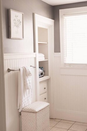 A bathroom with a white vanity, a towel rack, a framed picture, and a window with blinds. - That Corner Lot-Charming Downtown Home w/Side Yard (Troy)