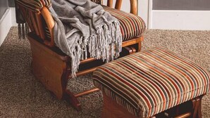 A wooden armchair with a striped cushion and a matching ottoman. - That Corner Lot-Charming Downtown Home w/Side Yard (Troy)