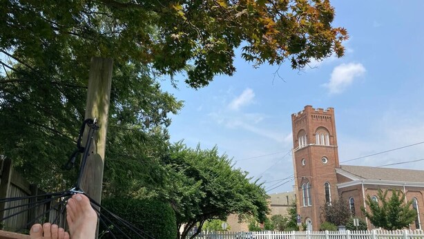 A hammock tied to a wooden post with a view of a brick church with a bell tower. - That Corner Lot-Charming Downtown Home w/Side Yard (Troy)