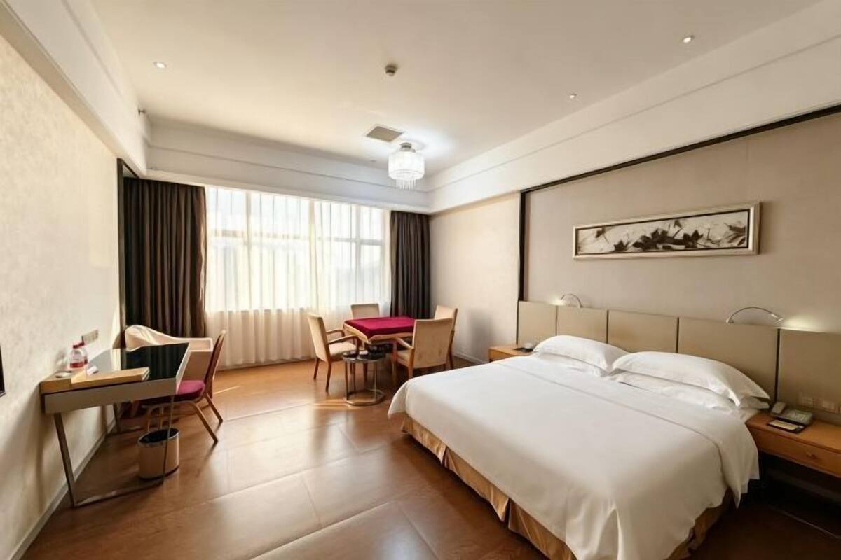 Habitación de hotel con cama, escritorio, silla y un cuadro en la pared.