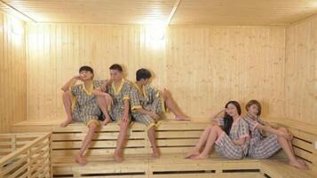 Una sauna de madera con bancos y personas sentadas.