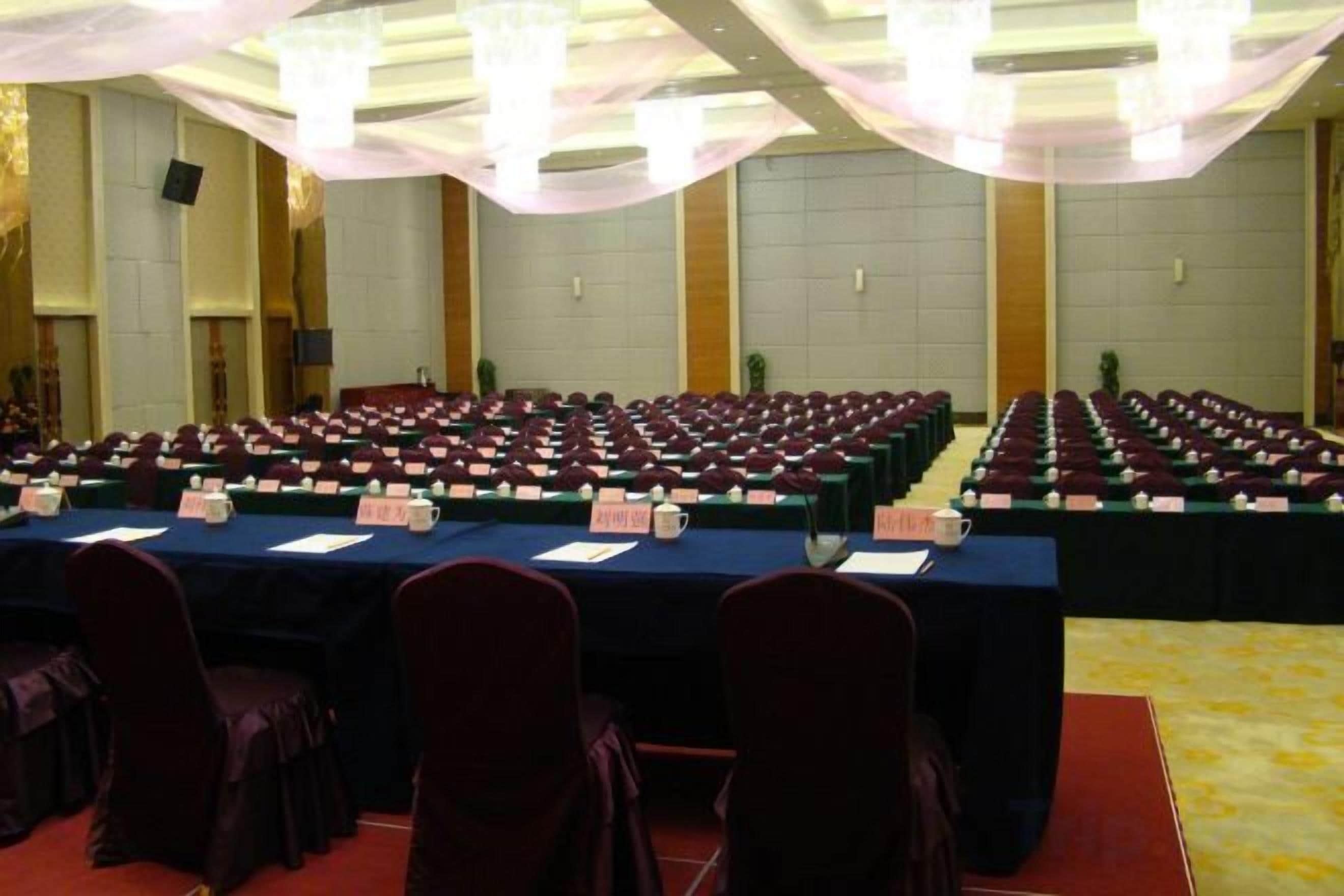 Un salón de conferencias con mesas y sillas dispuestas en filas, tarjetas de identificación y micrófonos.
