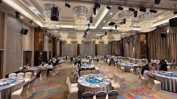 Un salón de banquetes con mesas redondas, sillas y piso alfombrado.