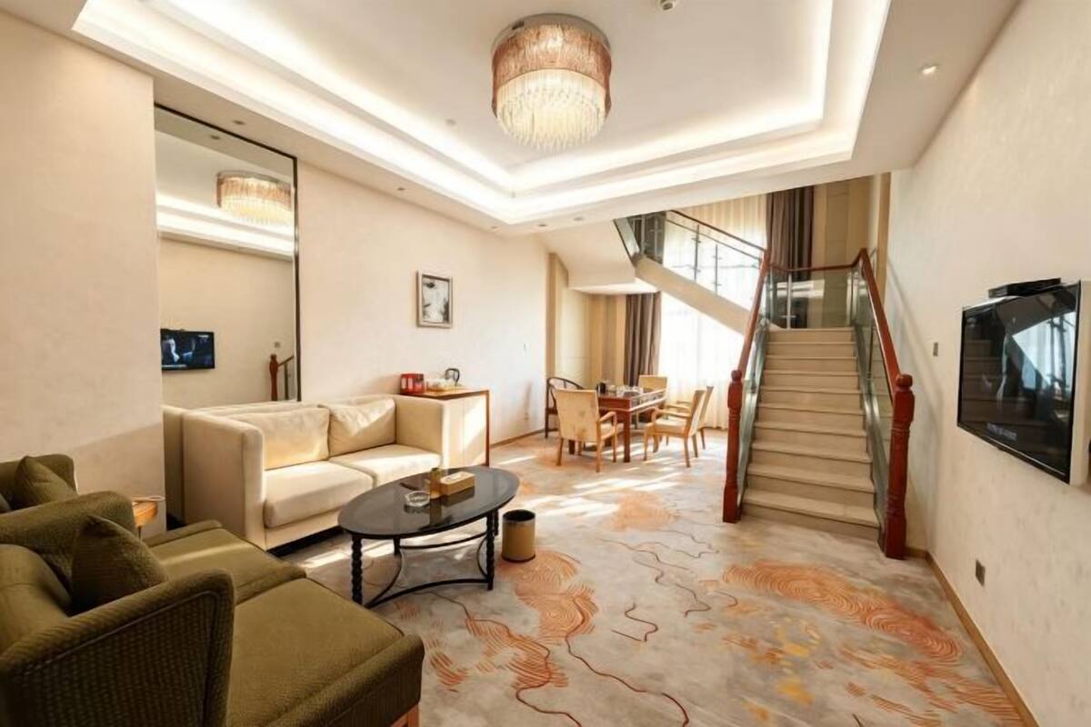 Amplia sala de estar con sofá, mesa de centro y una escalera que lleva a un balcón.