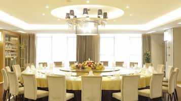 A round dining table with chairs, a chandelier, and a floral centerpiece.