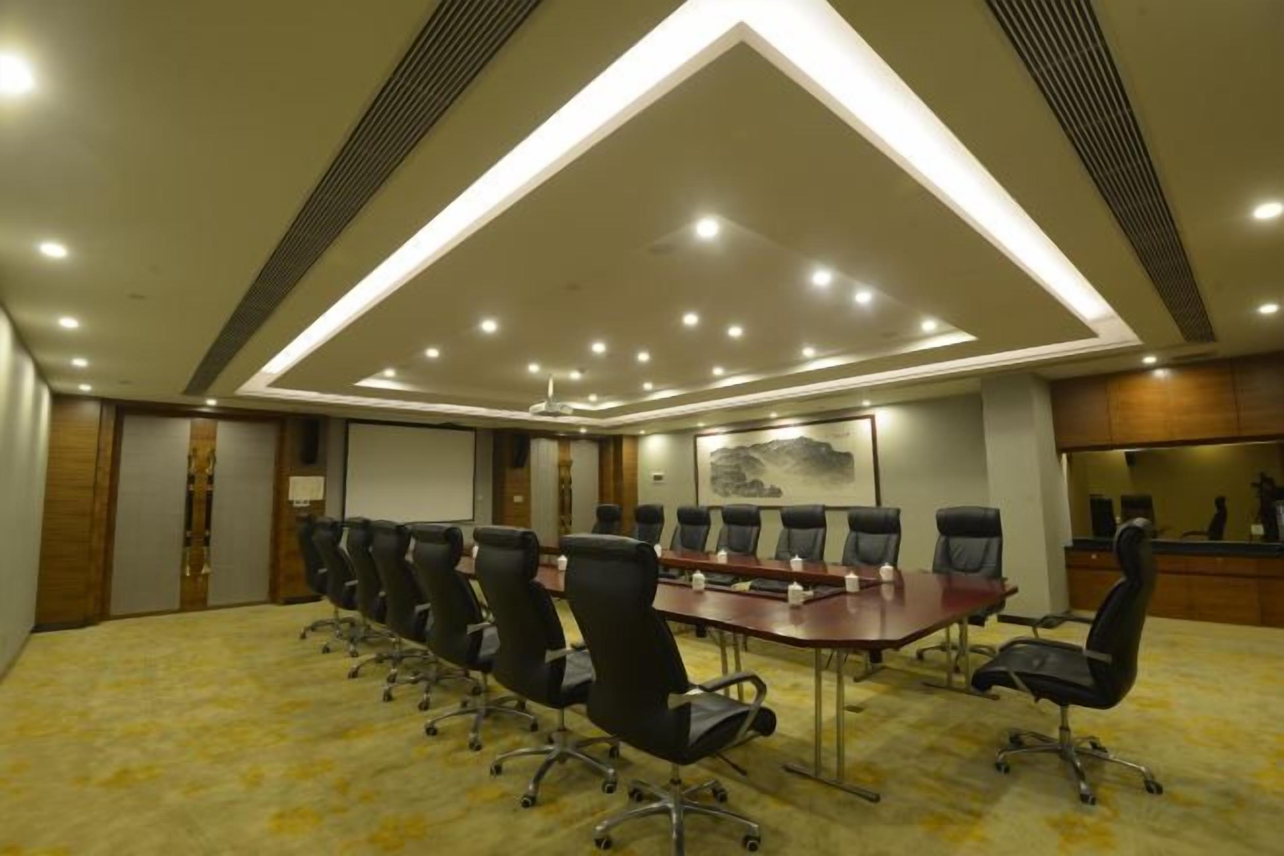 A conference room with a long table, multiple chairs, and a ceiling light fixture.