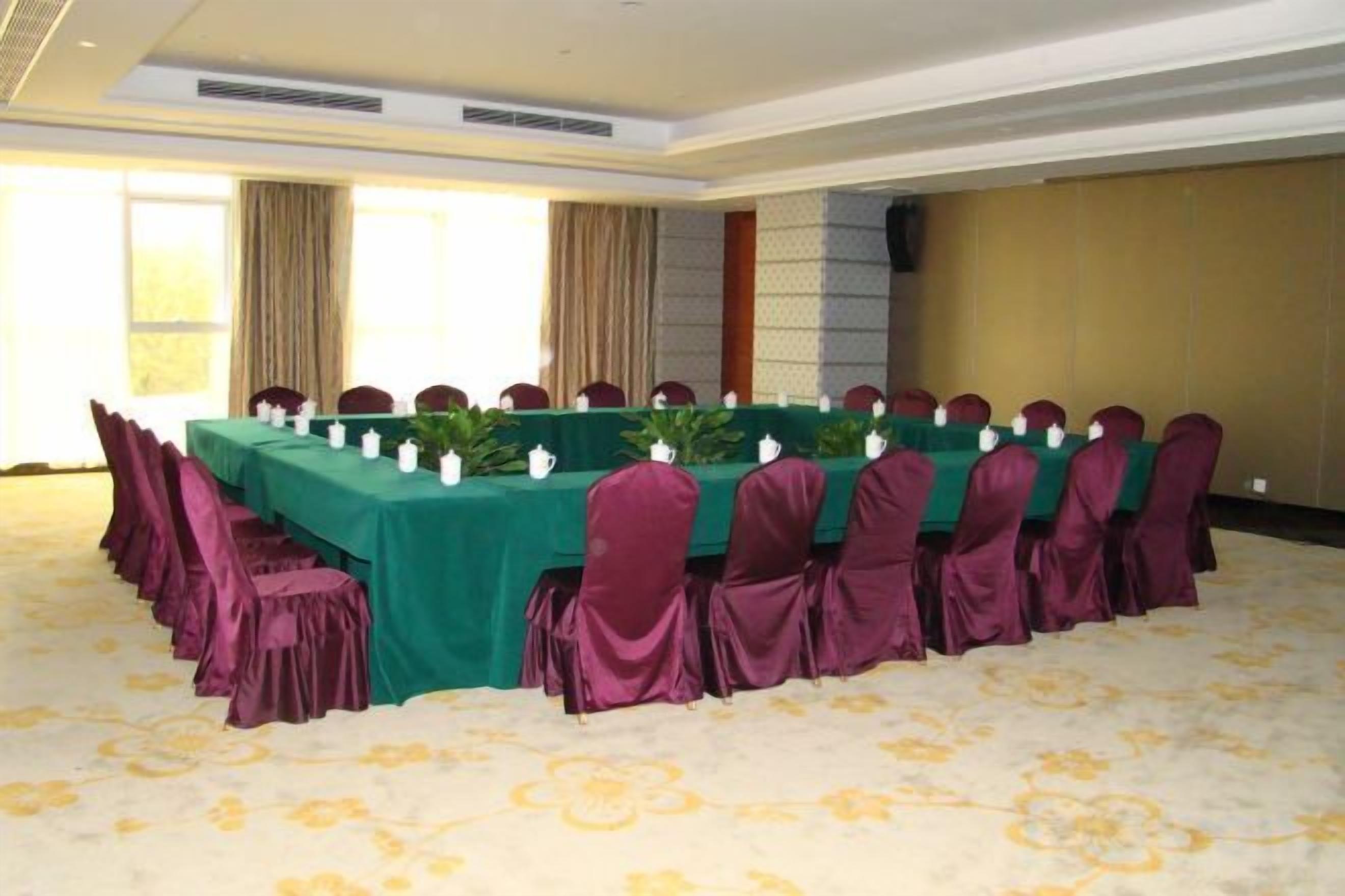 A conference room with a long table, chairs, and a carpeted floor.