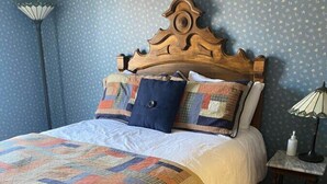 Un dormitorio con una cama de madera, un colcha, una mesita de noche y una lámpara.