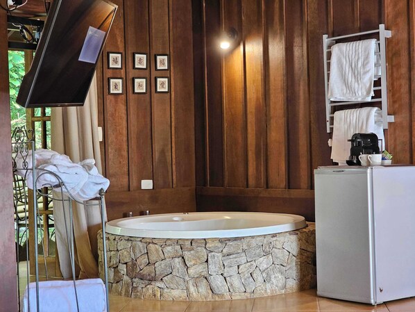 A bathroom with a stone-tub, wooden panel walls, a white sink, and a towel rack.