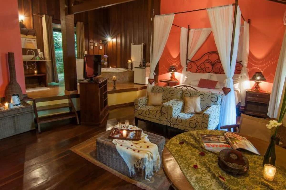 Um quarto acolhedor com uma cama, um sofá, uma mesinha e uma lareira.