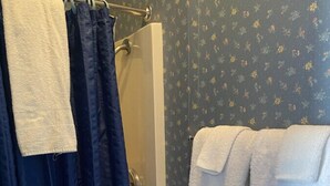 A bathroom with a shower curtain, a towel rack with a white towel, and a toilet paper holder.
