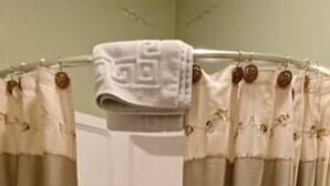 A bathroom with a shower curtain, a bathtub, and a towel hanging on the curtain rod. - AH #18 · AH #18 King/Jacuzzi Suite/Fridge/Micro (Wabasha)