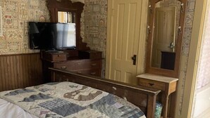 A bedroom with a bed, dresser, television, and a mirror.