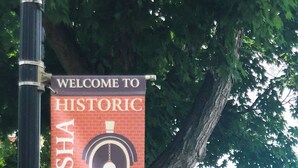 A welcome sign to Historic Wabasha Main Street with a brick building in the background.