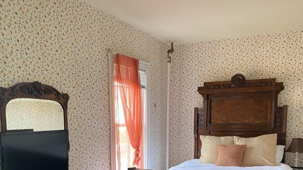 Ein Schlafzimmer mit einem hölzernen Bett, einem Schminktisch und einem Spiegel.