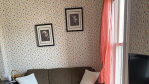 Ein Wohnzimmer mit einer Couch, einem Couchtisch, einem Fernseher und zwei gerahmten Bildern an der Wand.