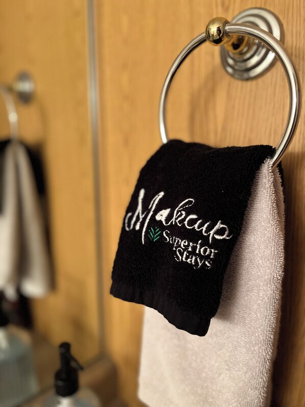 A black towel with embroidered text hanging on a metal towel ring. - AH #8 · AH #8 Queen Suite w/Tub/Shower (Wabasha)