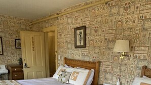 A hotel room with two single beds, a wooden headboard, a nightstand, a bedside table, a lamp, and a wall with a patterned design. - AH #36 · AH #36  Full x 2 w/Shower/Fridge/Micro (Wabasha)