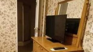 Une pièce comprenant une commode en bois, un miroir et un téléviseur.