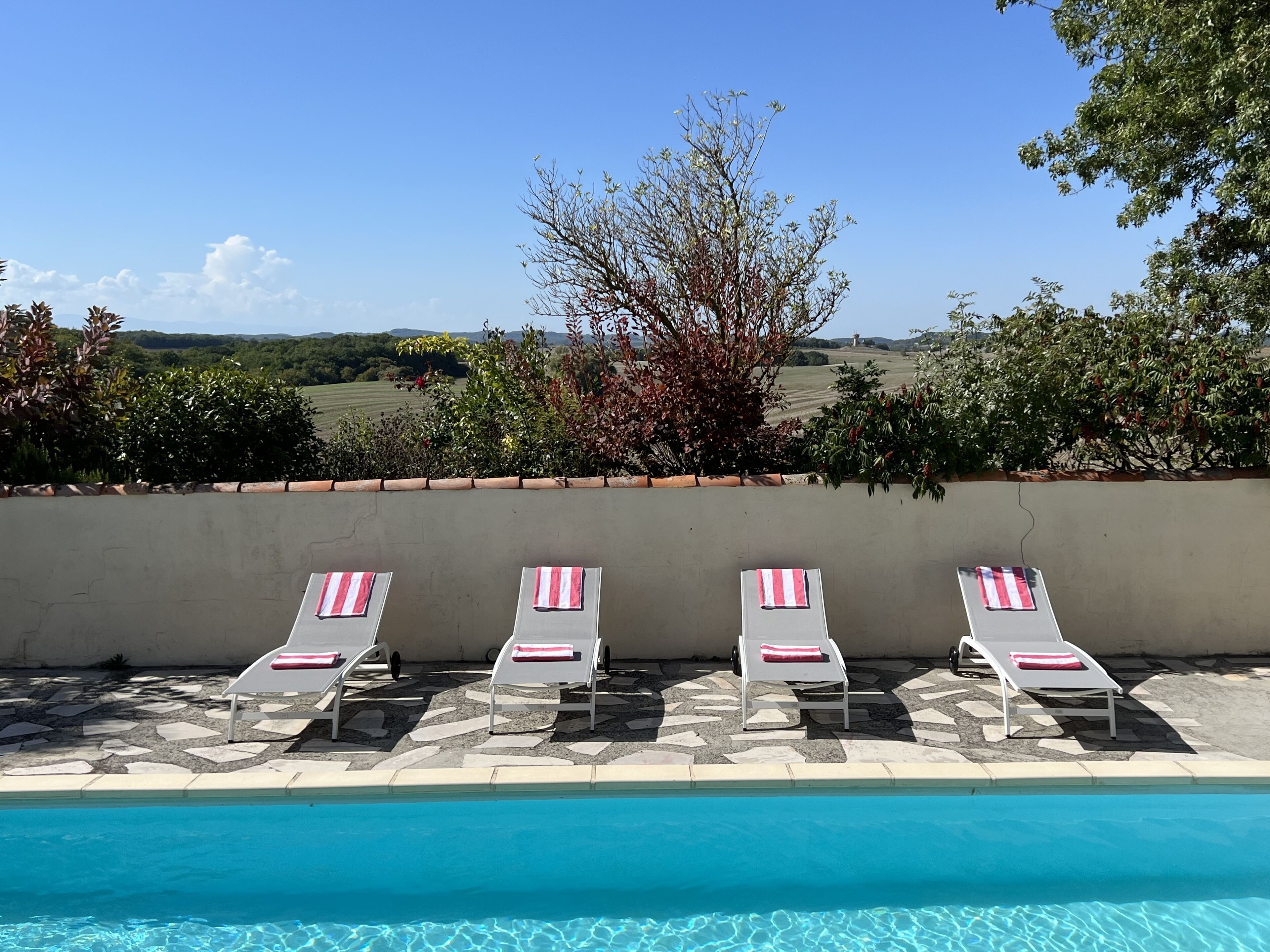 A poolside area with lounge chairs and a view of a landscape.