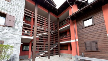Un edificio a più livelli con facciate in pietra e legno, arricchito da balconi e una scala.