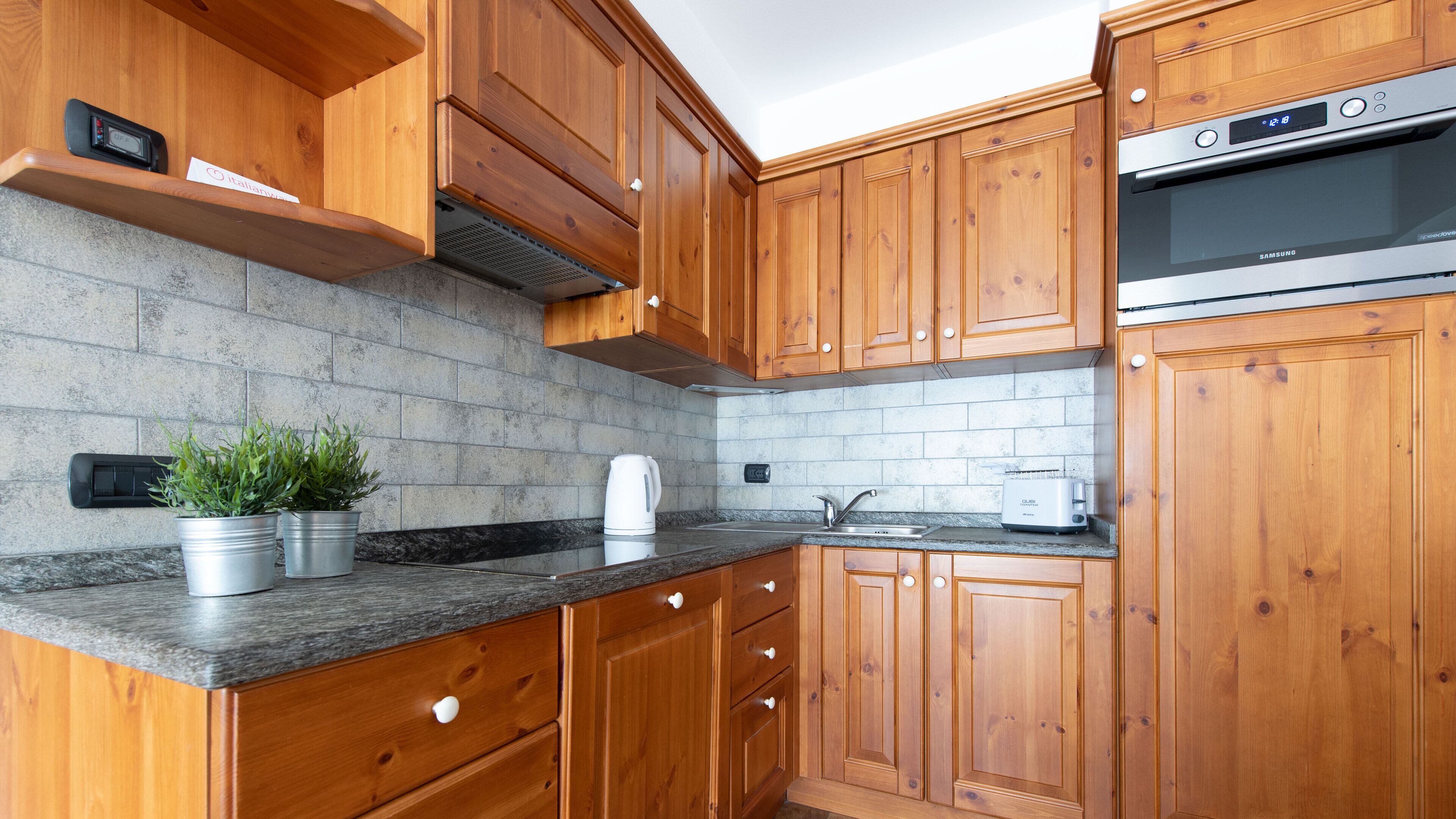 A modern kitchen with wooden cabinets, a built-in oven, a coffee maker, and a toaster.