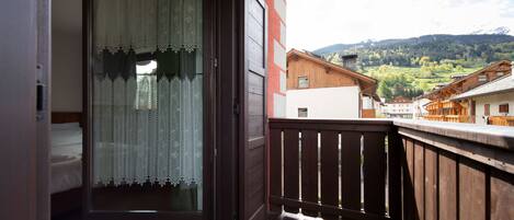 Un balcon doté d’une balustrade en bois, offrant une vue sur un paysage montagneux.