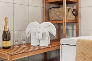 A wooden table with a bottle of Valdo champagne, two glasses, and a white elephant-shaped bathrobe. - Klara (Sandefjord)