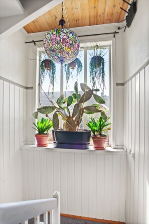 A room with a wooden ceiling, a stained glass chandelier, and potted plants on a window sill. - Klara (Sandefjord)