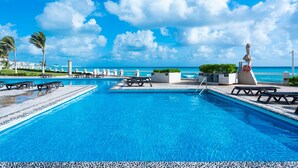 Ein Poolbereich mit Liegestühlen und einem Rettungsring mit Blick auf einen Strand.
