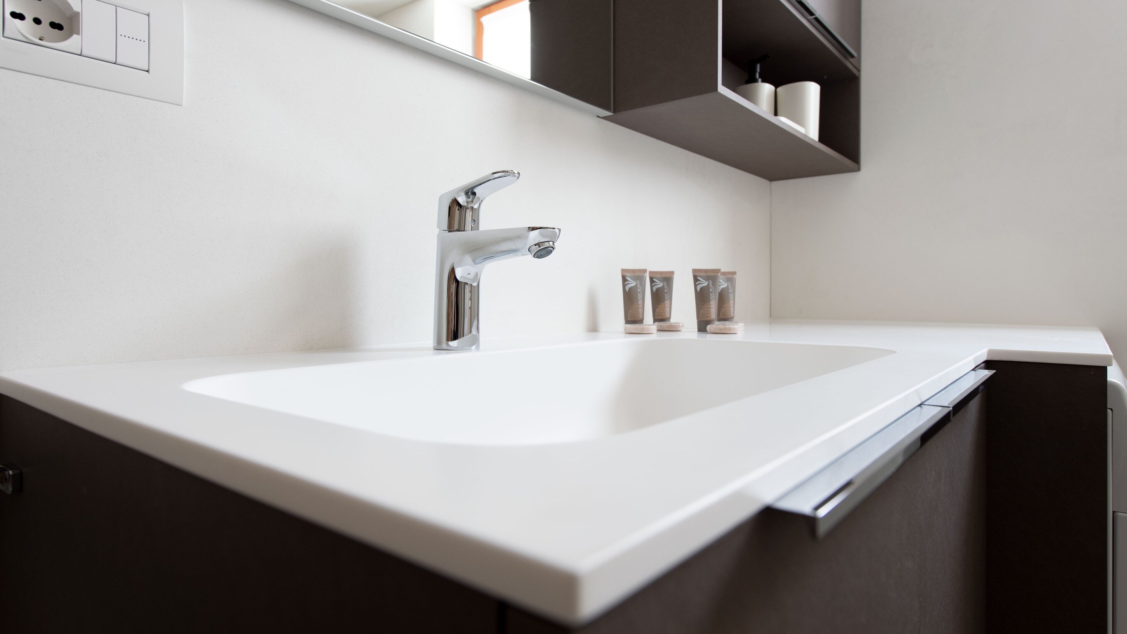 A modern bathroom with a white sink, chrome faucet, and dark cabinetry.