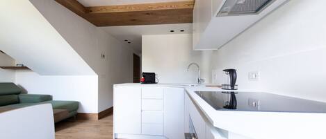 A modern kitchen with white cabinetry, a wooden ceiling, and a built-in stove.