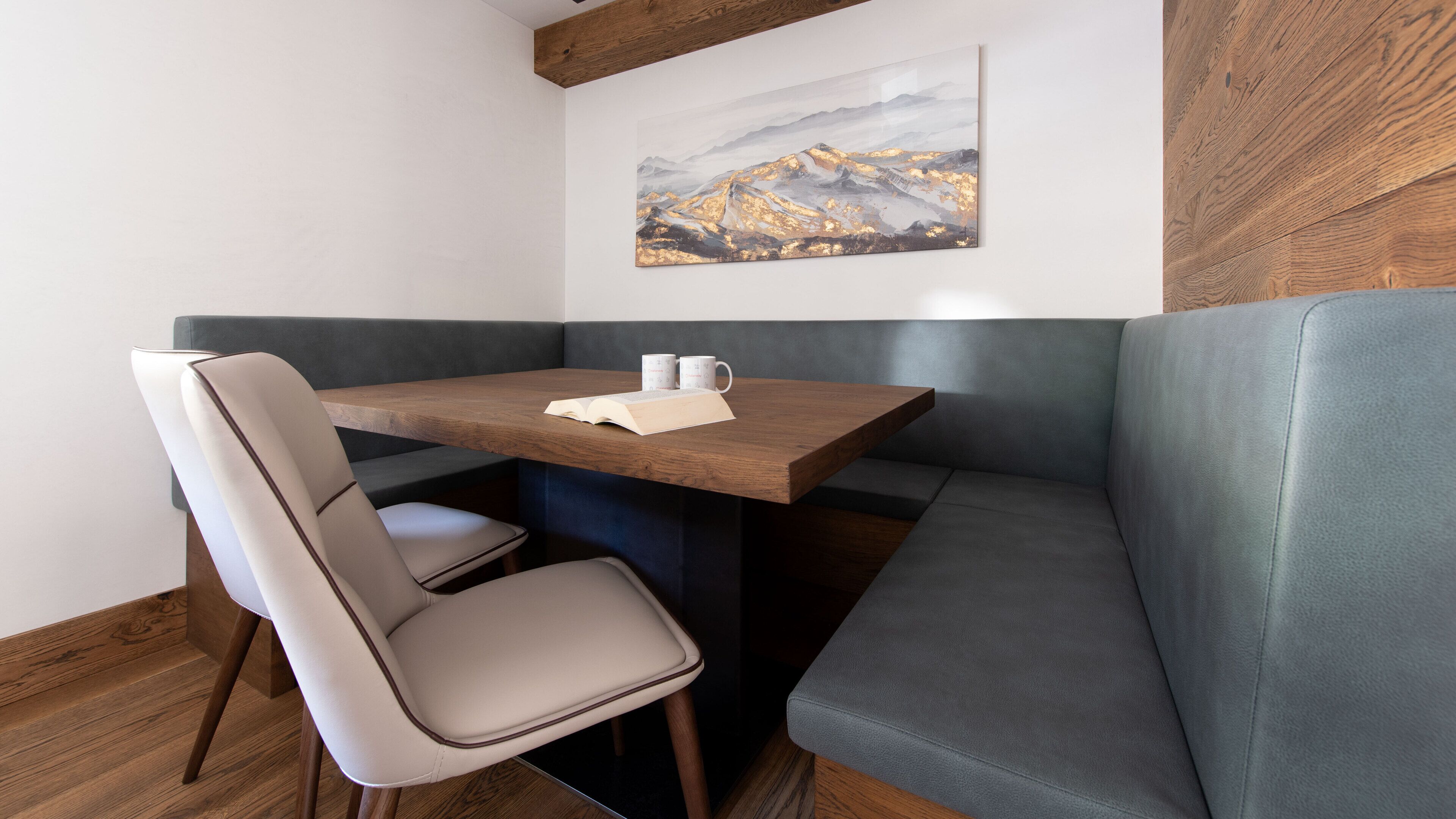 A corner seating area with a wooden table, cushioned chairs, and a bench.