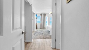 Un couloir orné d’un tapis à motifs qui mène à une chambre avec vue sur la mer.