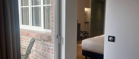A hotel room with a large window, a bed, a desk, and a chair.
