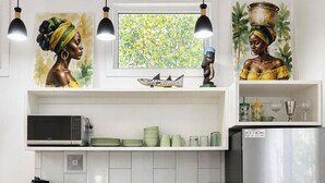 Ett modernt kök med vita skåp, ett kylskåp i rostfritt stål och ett fönster med utsikt över grönområden.