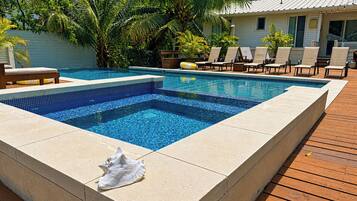 Piscina retangular com borda revestida e um deck de madeira ao redor.