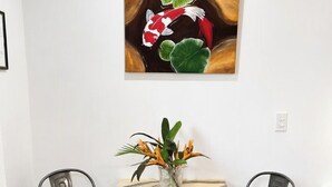 Una mesa de comedor con un florero, dos sillas y un cuadro en la pared.