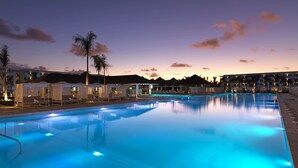 A swimming pool with lounge chairs and umbrellas, surrounded by hotel buildings and palm trees. - Paradisus Grand Cana - All Suites - All Inclusive (Punta Cana)