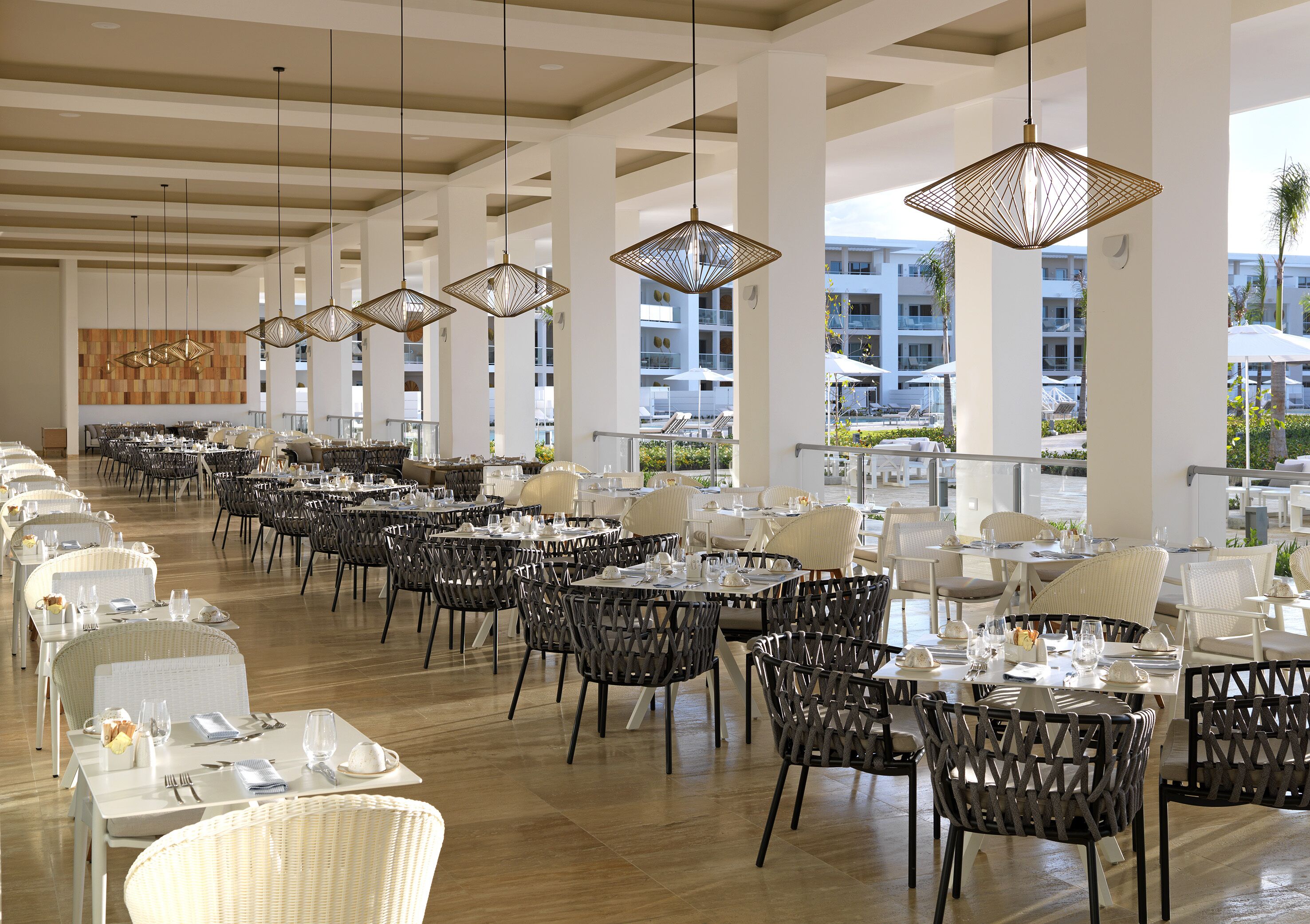 A spacious dining area with multiple tables and chairs, large windows offering views of the surrounding buildings and landscape.