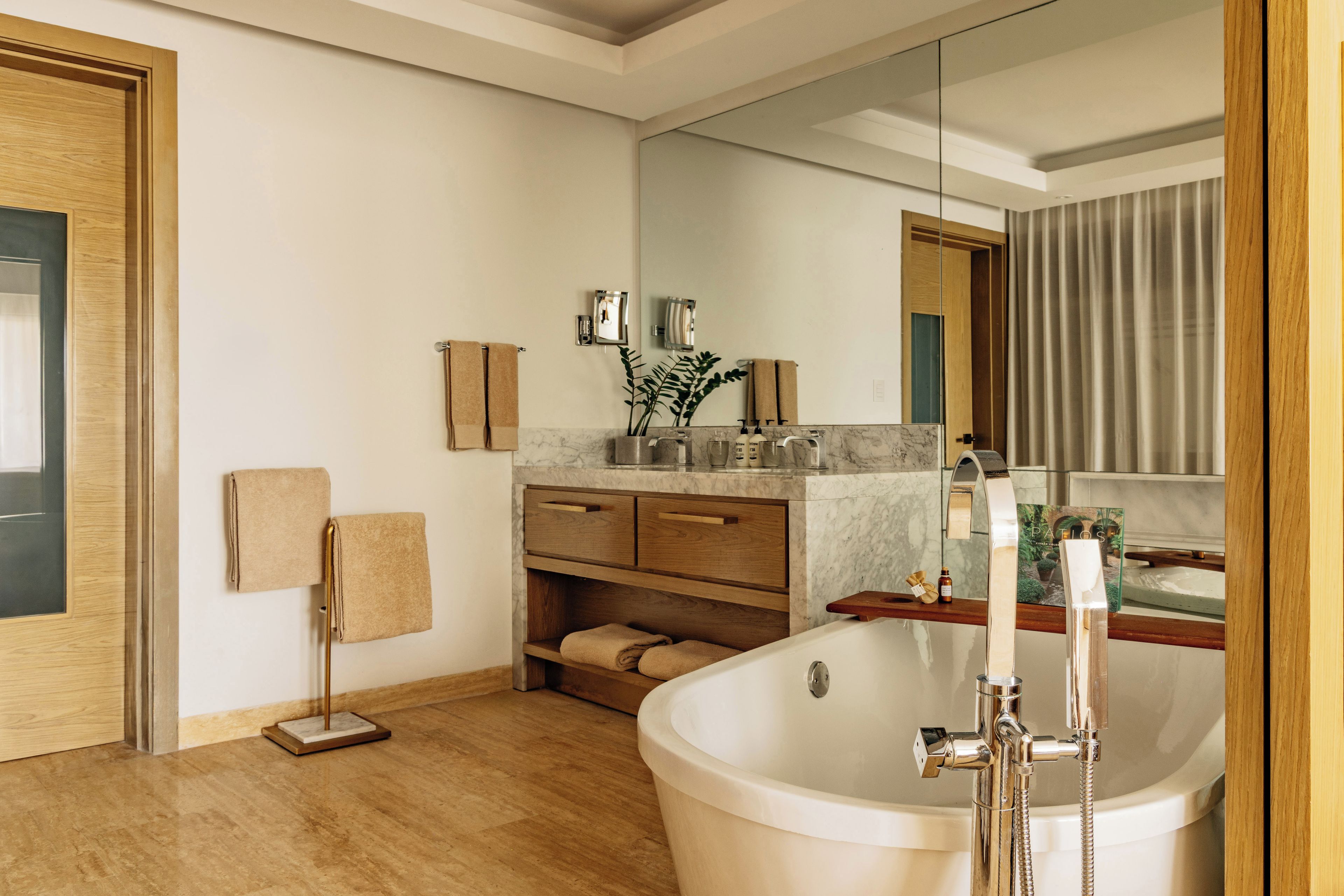 A modern bathroom with a freestanding bathtub, wooden vanity, and a large mirror.