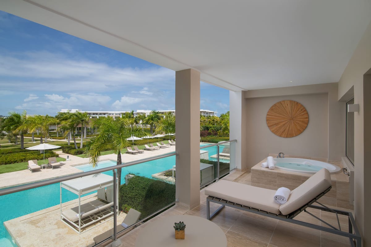 A balcony with a view of a swimming pool and a spa area.
