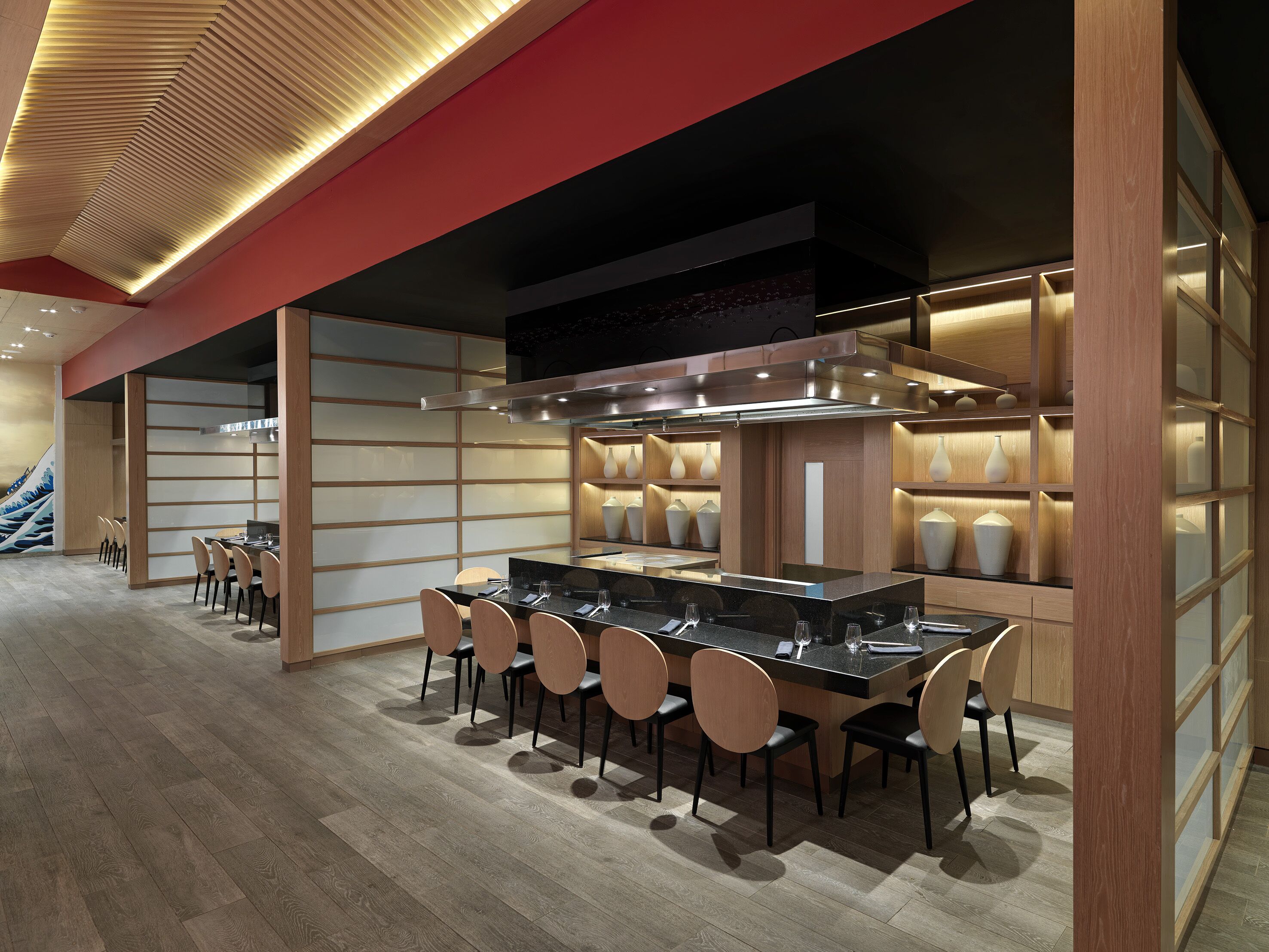 A modern kitchen with a central island, wooden panel walls, and a staircase in the background.
