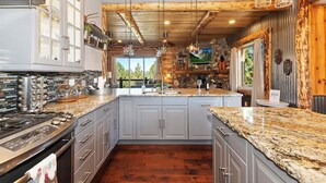 A kitchen with granite countertops, stainless steel appliances, and a large island. - Designer Chalet | Sauna · Fireplace · Mountain Views (Big Bear Lake)