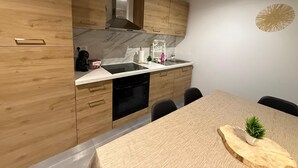 Une cuisine moderne avec des meubles en bois, un lave-vaisselle noir et un plan de travail en marbre.