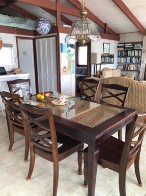 Enjoy meals in this cozy dining area with a wooden table and six chairs, surrounded by a bookshelf and a chandelier.