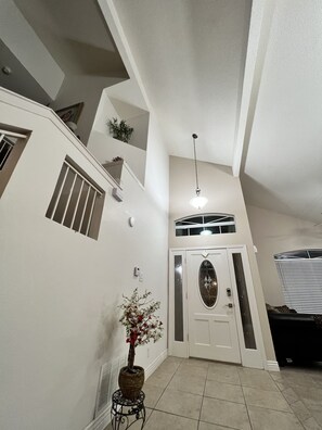 A hallway with a white door, a potted plant, and a staircase. - Cozy Beautiful house perfect for families (El Paso)